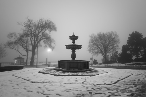 The Windsor, Ontario Riverfront Park on a foggy winter morning featuring a fountain overlooking the Detroit River.