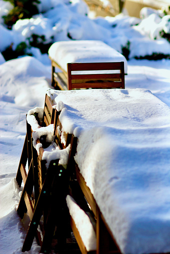 Fairfax, Virginia, USA - January 14, 2019: Freshly fallen snow covers patio chairs and tables on a backyard patio following a winter storm.