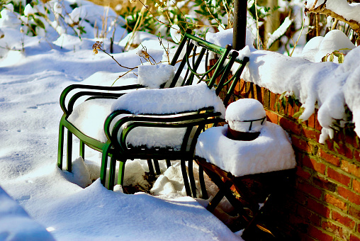 Fairfax, Virginia, USA - January 14, 2019: Freshly fallen snow covers patio chairs and a table on a backyard patio following a winter storm.