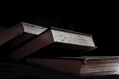 a pile of thick, dusty books on a dark background