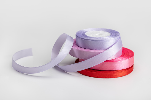 Satin ribbon for holiday packaging in a roll, close-up, studio shot.