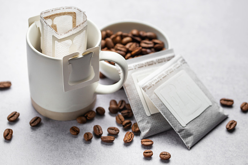 A  cup of freshly brewed drip coffee.  Drip coffee bag with ground coffee for brewing in a cup