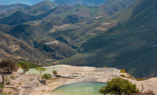 Girl on top of a white mountain with blue lakes and springs in Mexico hierve del agua