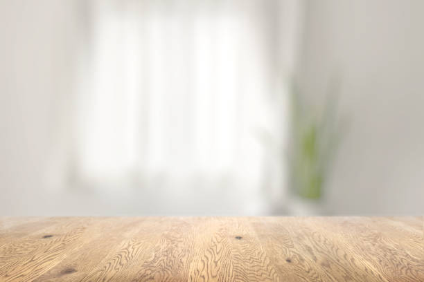 istock Blurred background seen through a wooden table with wood grain, background with depth, background image of a room with a window and houseplants 1959239644