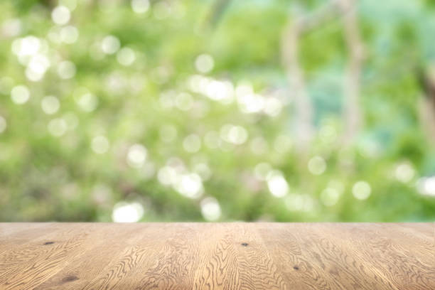 istock Blurred background seen through a wooden table with wood grain, background with depth, background image of green plants 1959239655