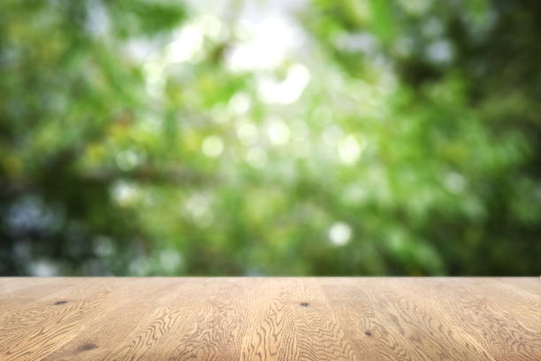 istock Blurred background seen through a wooden table with wood grain, background with depth, background image of green plants 1959240163