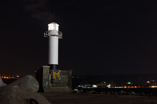 White lighthouse tower with glowing light. Night photo taken at Port of Varna, Bulgaria
