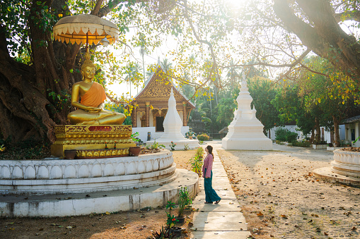 Woman exploring buddhist temple in Laos  at sunrise