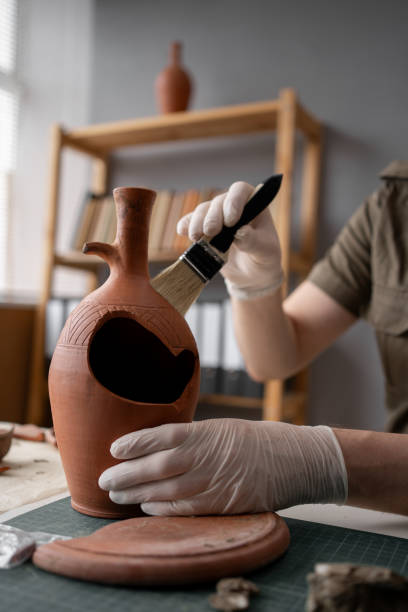 istock Archeologist working late night in office with brush and old vase. 1959329930