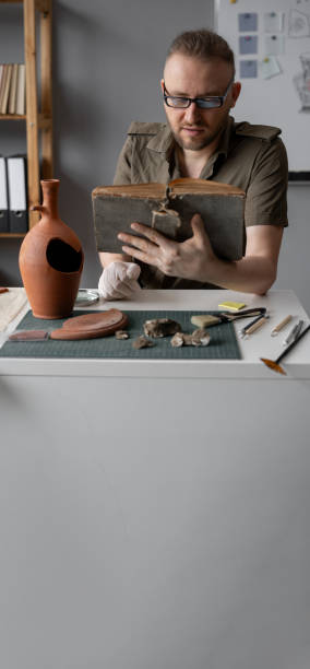 古書を読む考古学者、オフィスで古代文化や文明を研究する - tools for construction ストックフォトと画像