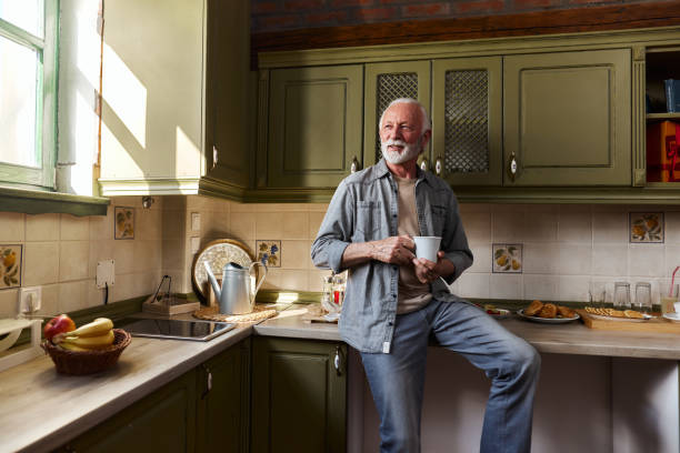 Happy mature man day dreaming during coffee time at home.