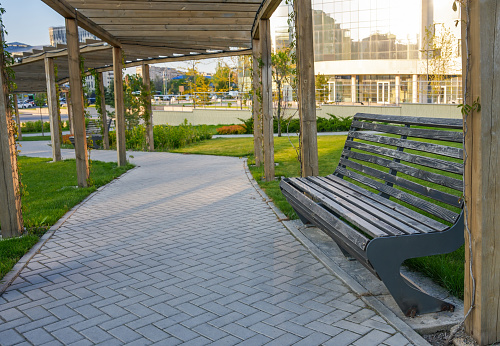 Almaty, Kazakhstan - May 4, 2023: Empty bench near the sidewalk in the park.