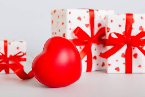 gift box with red bow and red heart on colored background. Perspective view. Flat lay.