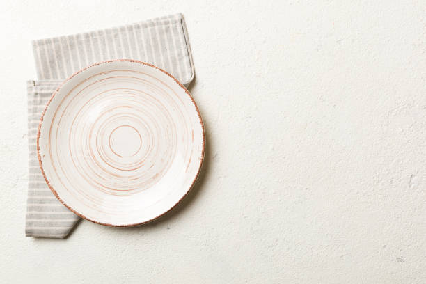 istock Top view on colored background empty round white plate on tablecloth for food. Empty dish on napkin with space for your design 1959363871