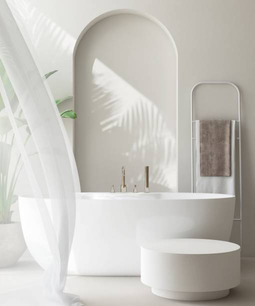 istock White round side table, bathtub, tropical banana tree in luxury design bathroom in sunlight, leaf shadow on cream arch wall 1959403953