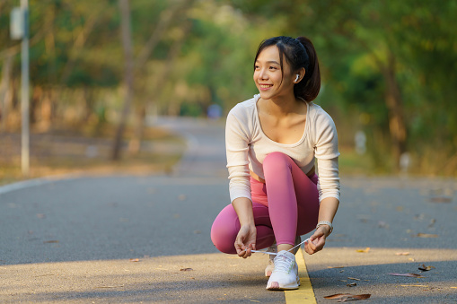 Running shoes - woman tying shoe laces. Female sport fitness runner getting ready for jogging outdoors on forest path in spring or summer.