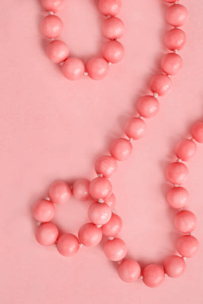 String of pink coral beads closeup on pastel pink studio background