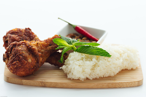 Asian white rice with deep fried chicken drumstick meal on cutting board tray