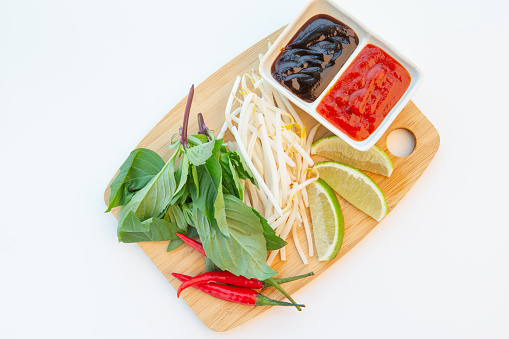 Tray with fresh beansprout, basil, lime, thai chili pepper with dipping sauce