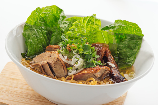 Asian BBQ Duck soup with egg noodle on cutting board tray
