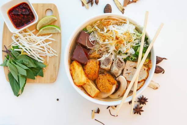 High angle view of Vietnamese shrimp based noodle soup with side dish on white background