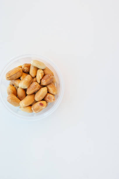 High angle view of Peeled roasted peanuts in small clear plastic bowl