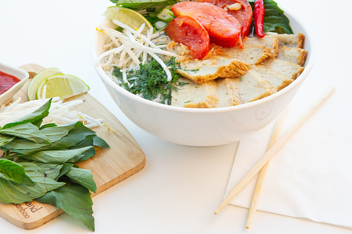 Vietnamese ham pho noodle vermicelli soup with veggie side dish on white background