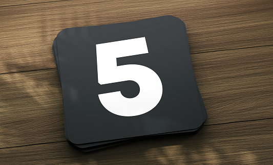 Placard with the number 5 on the wooden table. Finance Concept.