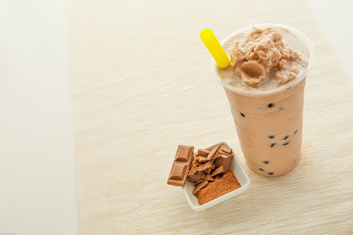 Asian chocolate smoothie in disposable cup on cream table runner