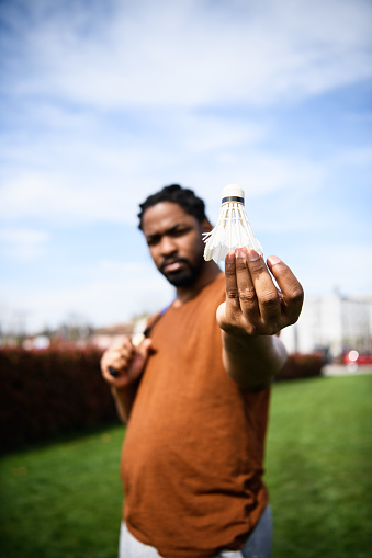 A Portrait of an African-American man in Public Park Who is Playing Badminton While Holding a Badminton Racket and Shuttlecock.