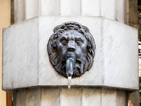 Cuneo, Italy - 14 July 2022: Drinking water in the city with a lion's bronze head tap for hot summer days