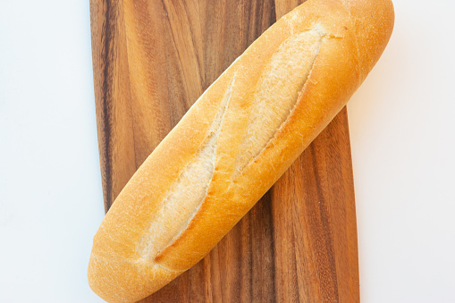 One Vietnamese baguette on wooden cutting board on white background