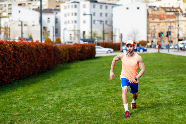 close-up shot of vibrant green grass blades in the foreground, with a blurry runner in white shoes passing on a dirt path, capturing nature and fitness