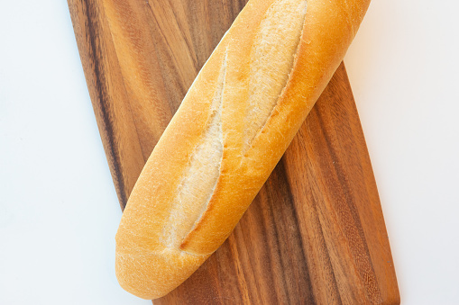Vietnamese baguette on wooden cutting board on white background
