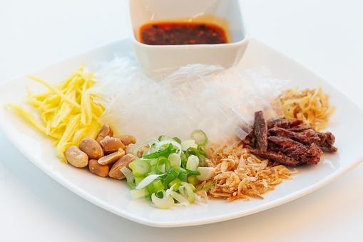 Vietnamese dry rice paper with variety of items with hot chilli sauce dipping on white background