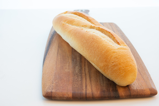 One Vietnamese baguette on wooden cutting board on white background