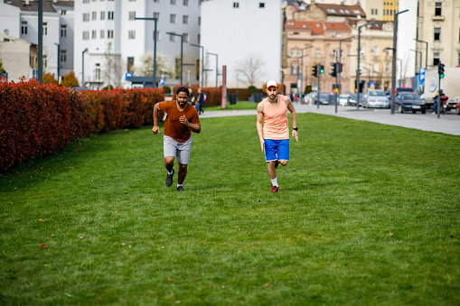 A Cheerful African Man and his Friend are Jogging in the Public Park.
