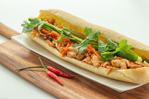 Vietnamese satay chicken baguette  with variety of veggie on wooden cutting board on white background
