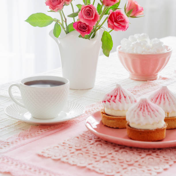 cup of coffee with dessert and roses on table