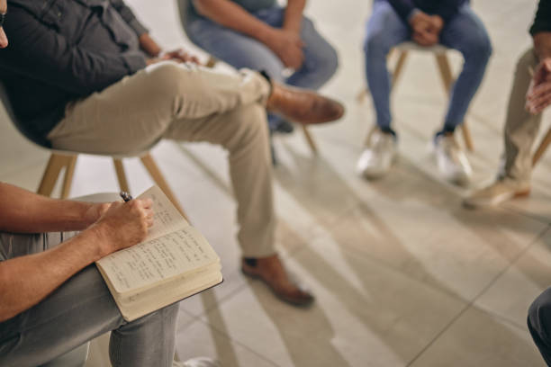 istock Support, therapy and people in group with psychologist and notebook, communication and community with help. Mental health, comfort and psychology notes, counseling with empathy and discussion 1959565618