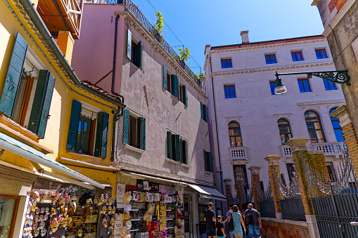 Old town of Italian City of Venice with souvenir shops and tourist family walking on a sunny summer day. Photo taken August 7th, 2023, Venice, Italy.