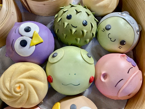 6 cute colorful character steamed buns lie in a bamboo steamer basket