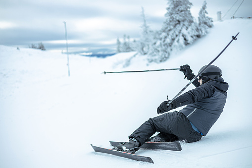 The challenging terrain of the slopes becomes evident as a skier falls while navigating the snowy mountains, showcasing the physical demands of winter sports