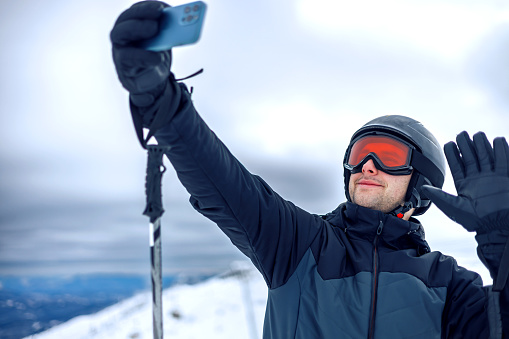 On a snowy hill, a young man stands looking away, smartphone in hand, illustrating the blend of outdoor adventure with the ever-present connectivity of wireless technology