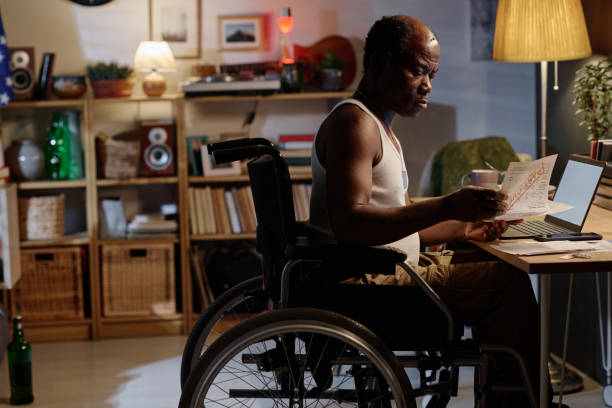 istock Serious Black Man in Wheelchair Doing Paperwork at Home 1959606677