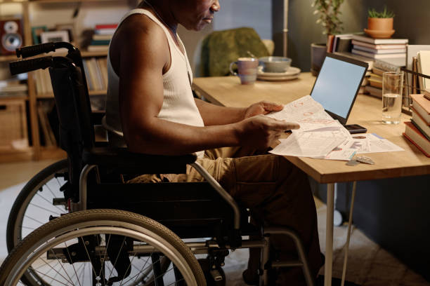 Black Man with Disability Looking Through Bills Sitting at Home