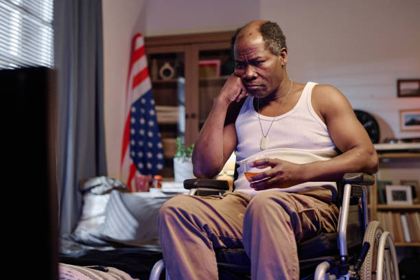 istock Extremely Bored Black Man in Wheelchair Looking at TV Screen 1959609399