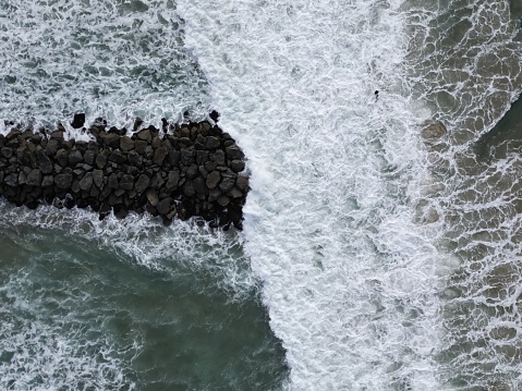A High-definition aerial photo of waves hitting rocks on the beach