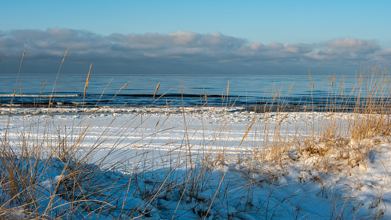 A serene union: the icy sea meets the golden whispers of winter's twilight on snowy shores.