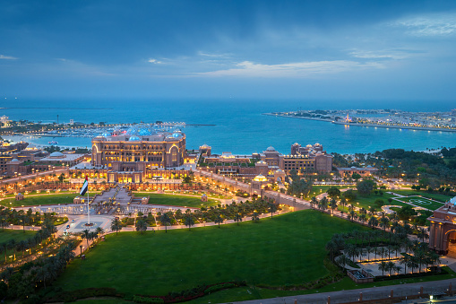 Abu Dhabi, United Arab Emirates - April 14, 2023: Emirates palace in Abu Dhabi top landmark skyline view with the city downtown in the United Arab Emirates capital city. Elevate your perspective with this breathtaking top view of the iconic Emirates Palace in Abu Dhabi, UAE. The opulent architecture of the palace is set against the backdrop of the vibrant city downtown, creating a stunning contrast that defines the capital's grandeur.
